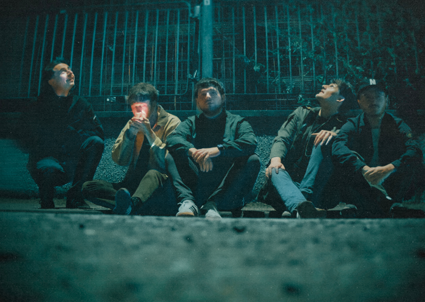 Members of the band 'Vida' sitting on a kerbx